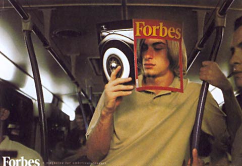 Ad of an individual standing in a bus and holding a magazine right in front of the head.