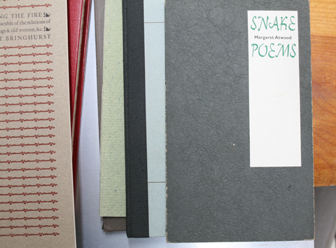 several covers of books on top of each other with a book called 'Snake Poems' on top of the pile
