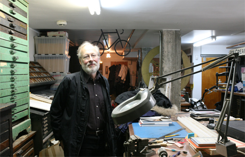 Glenn Goluska in his studio surrounded by cases for letters and an office table