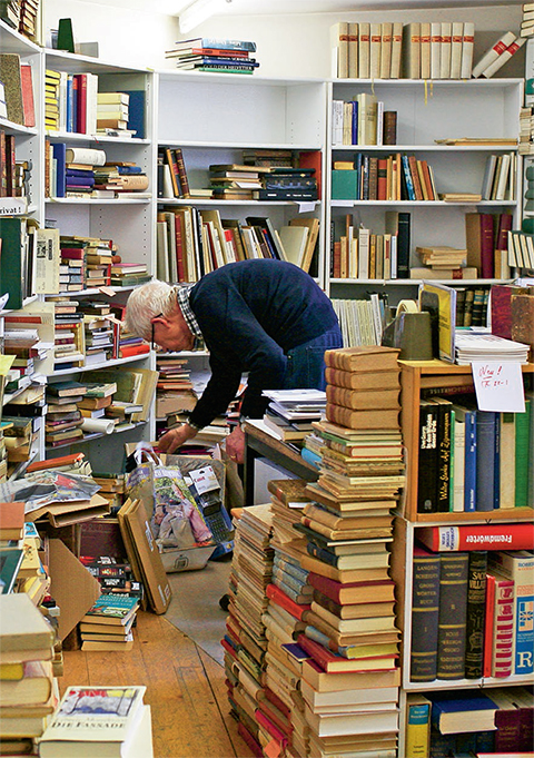 Elderly man surrounded by bookshelves and books