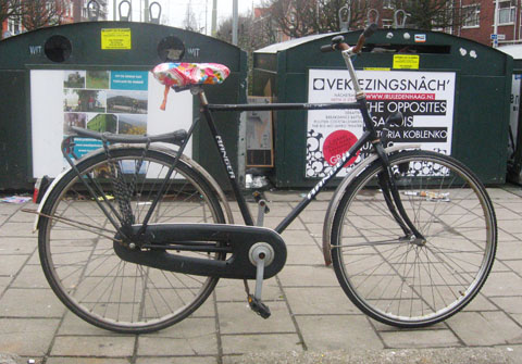 black male bike with recycling containers in the background