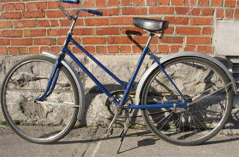 blue bike with brick house in the background