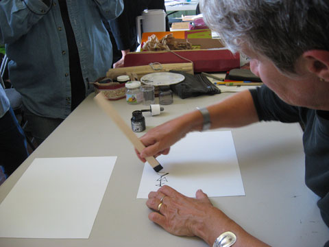 Denise Lach using the wood as a writing tool