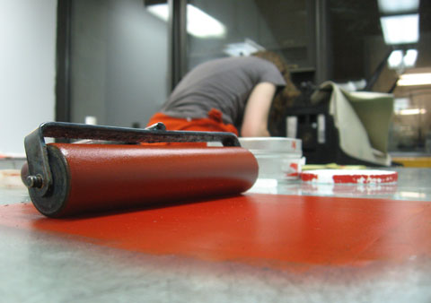 A roller with red color in the foreground, Brigitte working in the back