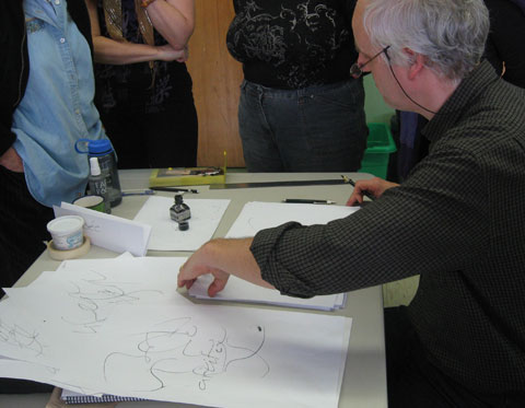 Calligrapher demonstrating writing with a pen to a group of people standing around a table