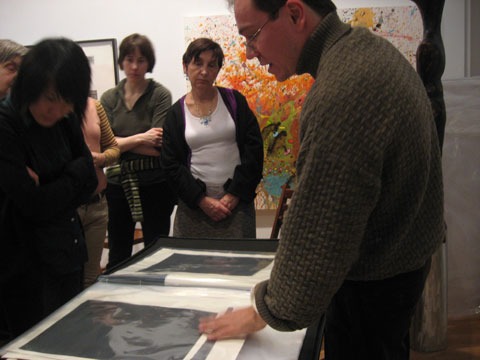 Paolo C. Penna is presenting his work to a group standing around a table