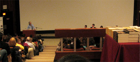  David Suzuki  at Concordia University hall building speaking at the front podium with a large public