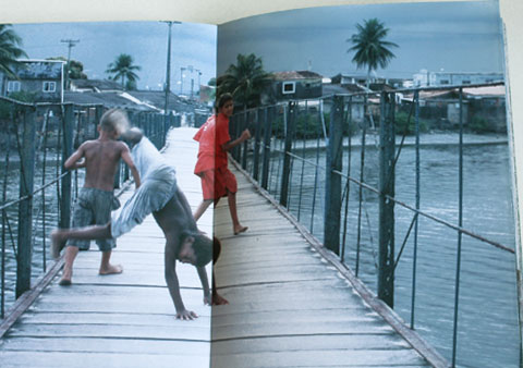 Double-page of the Ilha de Deus Exposition Catalogue with an image of playing boys on a bridge