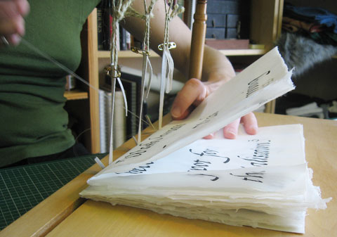 Bookbinder sewing the pages of the book